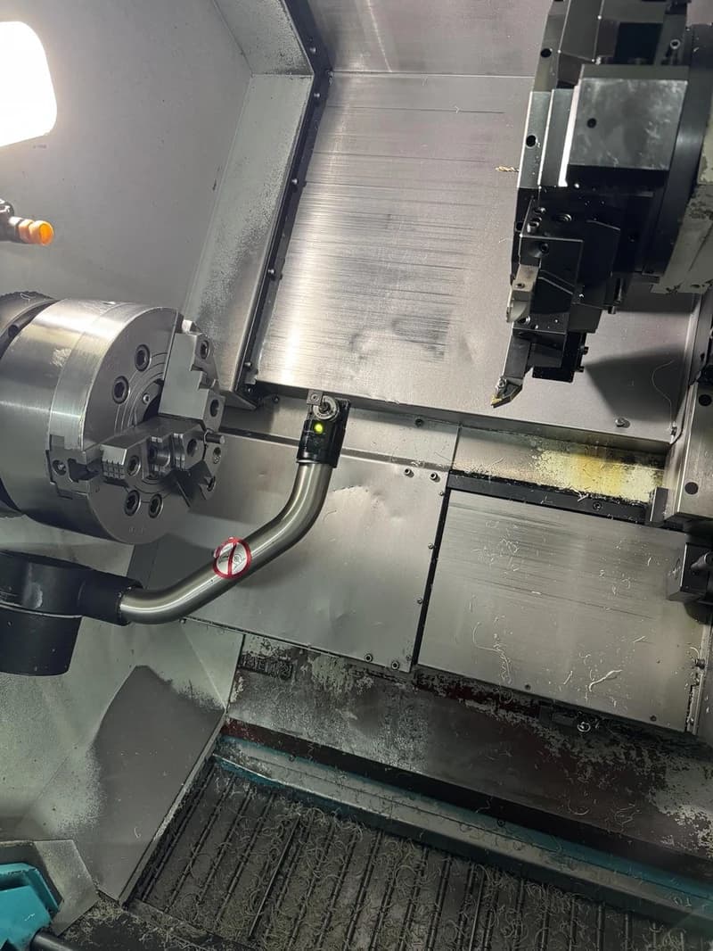 Eine CNC-Drehmaschine in einer Werkstatt, die Metall bearbeitet. Die Maschine ist mit einem Werkzeugrevolver und einer Spindel ausgestattet.