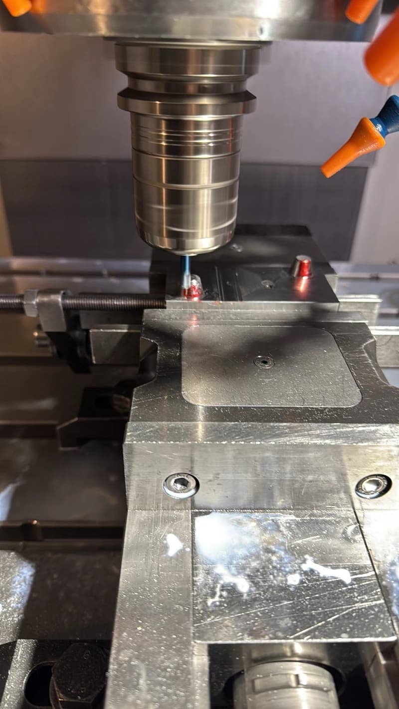 Eine CNC-Maschine führt eine Metallbearbeitung durch. Der Fräser ist im Einsatz und Kühlmittel wird zugeführt.