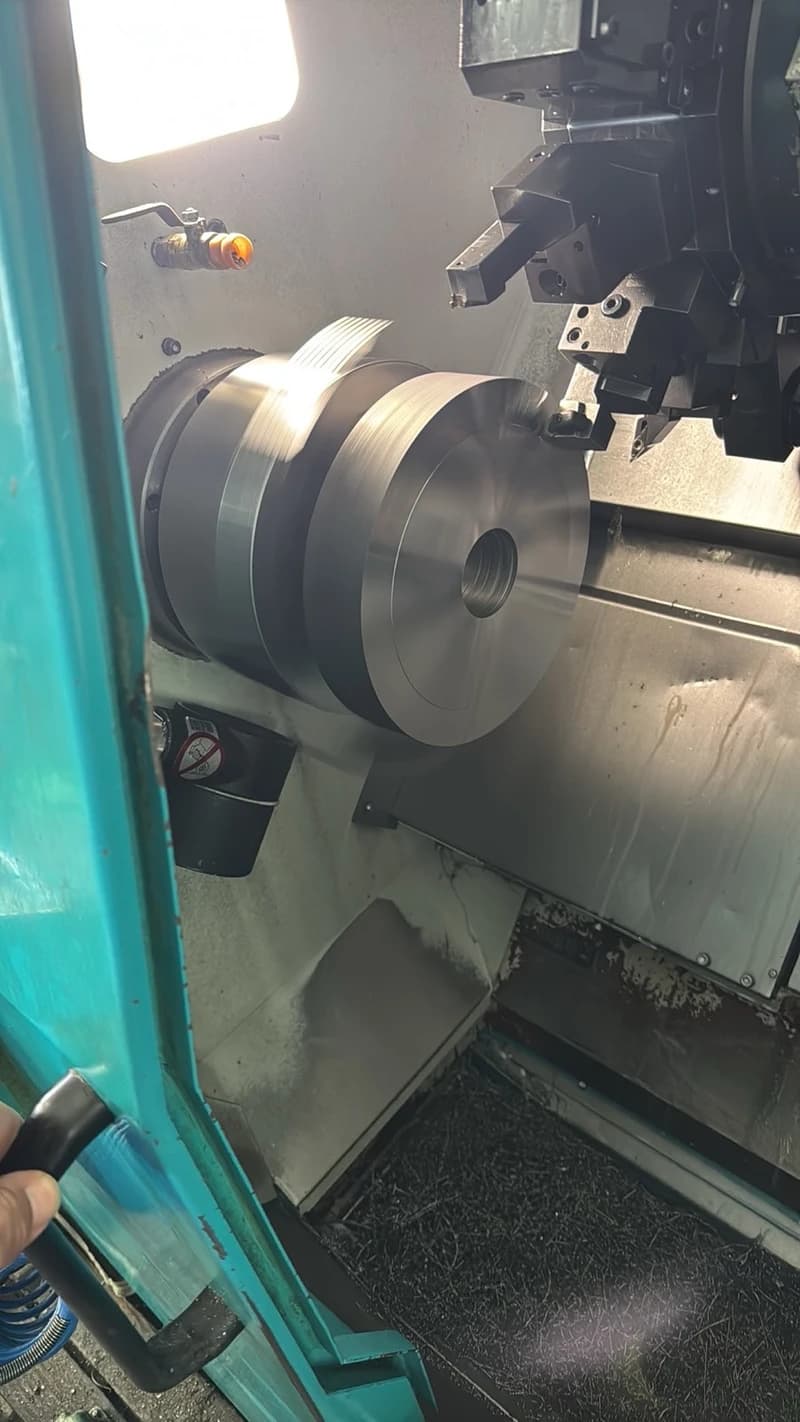 Eine Drehmaschine bearbeitet ein metallisches Werkstück. Die Maschine ist mit einem Werkzeugkopf ausgestattet, der das Werkstück formt.