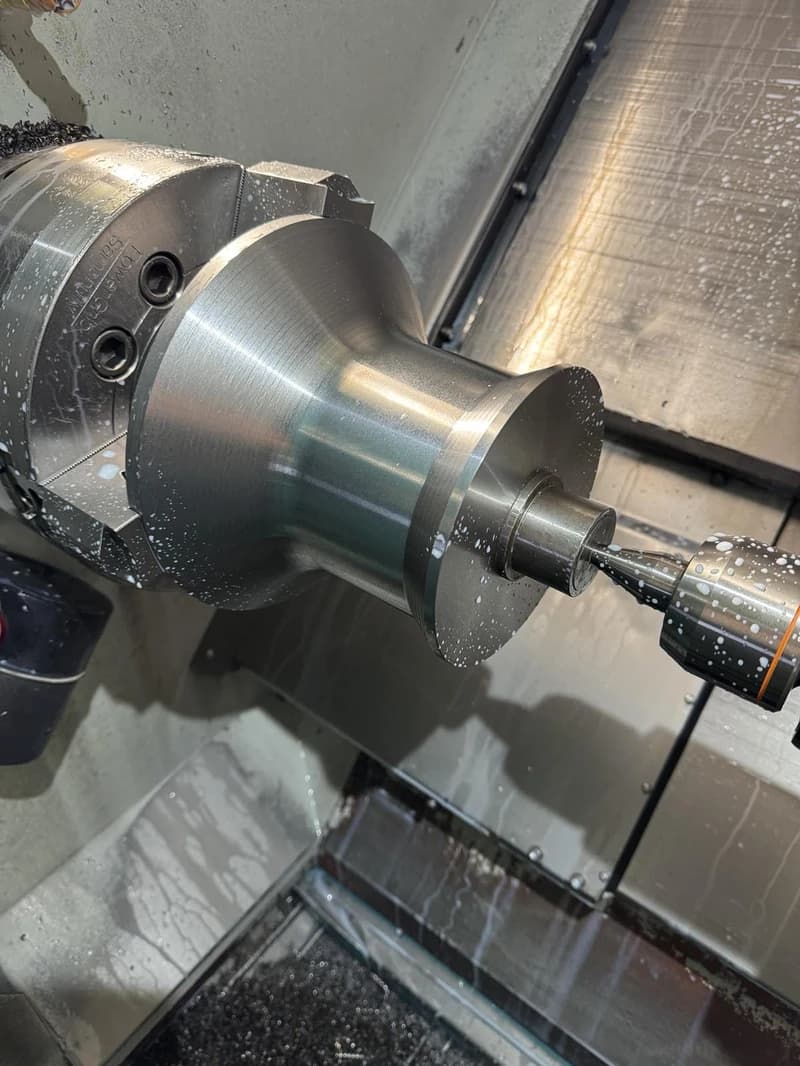 Ein Werkstück wird auf einer Drehmaschine bearbeitet, wobei Kühlmittel verwendet wird. Die Maschine ist mit Metallspänen bedeckt.